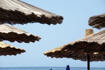 Straw beach umbrellas on the beach by the sea, Straw beach umbrella, Old Budva, Montenegro
