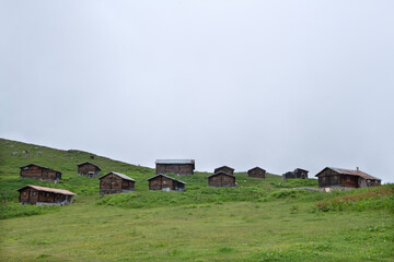 Obraz premium Highland landscape in cloudy and foggy weather. Highland houses made of stone and wood. Wooden plateau houses built on the hill. Wooden plateau houses in Turkey. Sal Plateau Rize Türkiye. 
