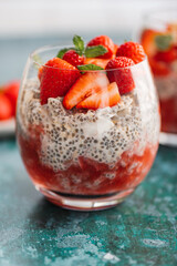 Healthy chia pudding in a glass with fresh strawberries made from almond milk and berry juice. Perfect breakfast for healthy start of the day