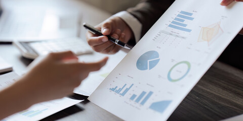 Closeup hand of Chief and employee discuss monthly earning graph together in the office