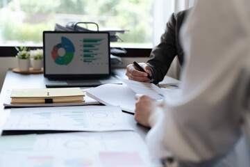 Chief and employee discuss monthly earning graph with laptop together in the office