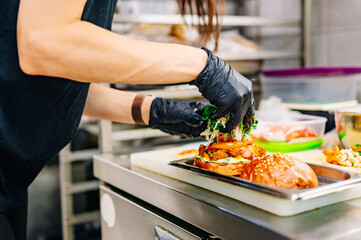 chef hand cooking cheese burger with vegetables and meat on restaurant kitchen