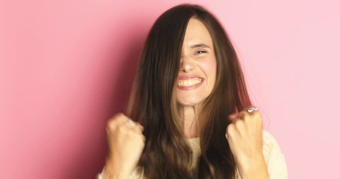 Brunette girl shocked, saying WOW. Pretty excited woman smiling, jumping, pleasantly surprised to camera isolated pink background. Winning girl celebrate jumping with ecstatic face expressions. 