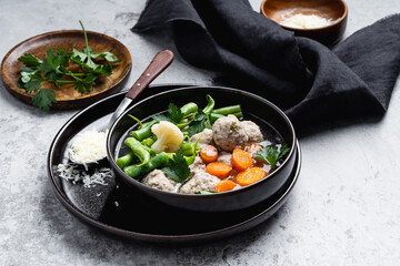 Meatballs soup, minestrone soup with  with seasonal vegetables and herbs, served with parmesan cheese