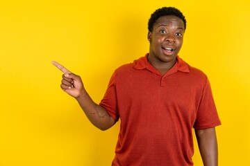 Emotive Young latin man wearing red t-shirt over yellow background keeps jaw dropped from shock...
