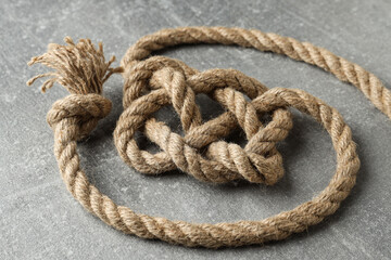 Thick knotted rope close-up on gray background