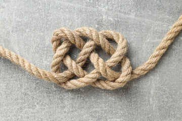 Thick knotted rope close-up on gray background