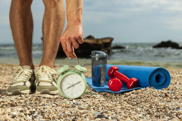 A watch, sneakers on a person, sports accessories on the beach