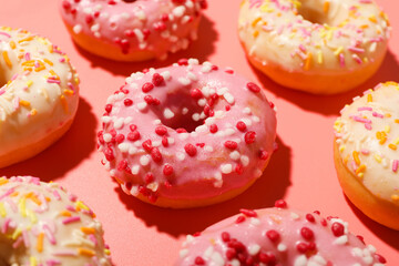 Glazed colored donuts on pink background, close up