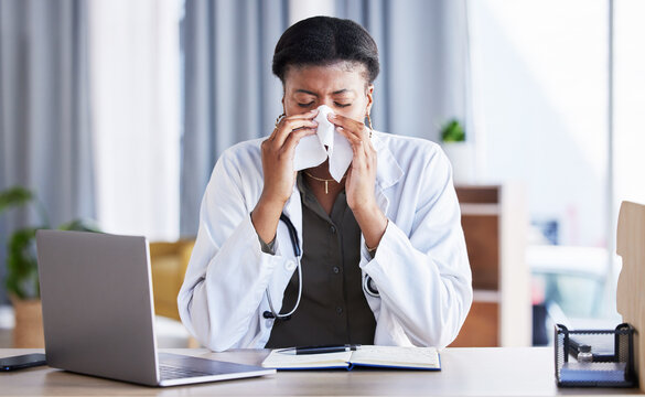 Sick, Doctor And A Black Woman Blowing Nose In An Office As A Healthcare Employee At A Desk. Table, Hospital And An African Nurse Or Medical Worker Sneezing Into A Tissue With A Virus Or Flu