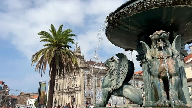 video of fountain of Lions, 19th century fountain in Parada Leitao Square in historic city of Porto in Portugal. The beautiful Carmo church on blurred background.