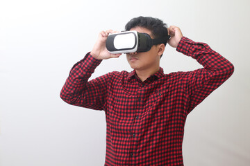 Portrait of Asian man in red plaid shirt getting ready and using Virtual Reality (VR). Isolated image with copy space on white background