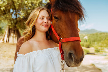 Young beautiful woman with horse in countryside during summer. Cowgirl enjoying with her horse.