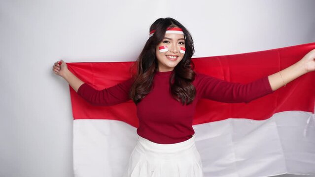 Happy excited Indonesian woman holding Indonesia's flag to celebrate Indonesia Independence Day isolated over white background.