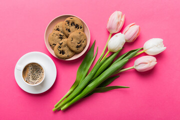 Cup of coffee mug with coffee, cookies and tulips on a colored background. Greeting spring card top view