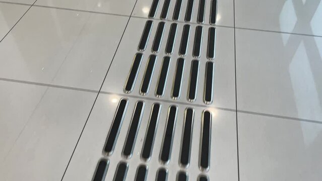 Blind pedestrian walking and detecting markings on tactile paving with textured ground surface indicators for blind and visually impaired. Blindness aid, visual impairment