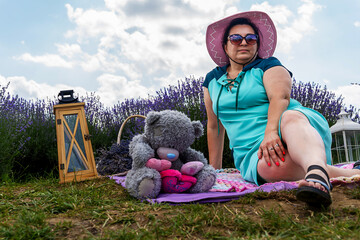 Woman sitting on a picnic blanket in a lavender field , sunny day, enjoying summer time and dreaming. © Laslo
