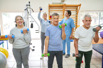 Therapists assisting elderly people exercising at rehab center