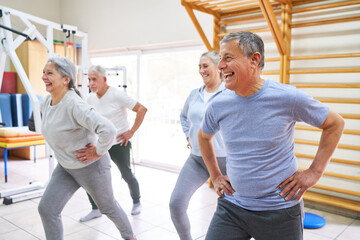 Happy senior males and females exercising at rehabilitation center