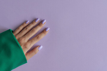Gelish manicure with purple nails on background of lavender color. Purple fingernails and green clothing - 627252846