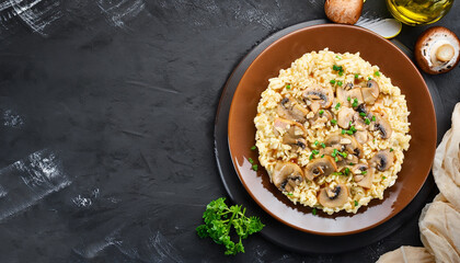 A dish of Italian cuisine - risotto from rice and mushrooms in a brown plate on a black slate...