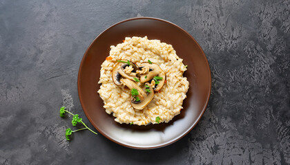 A dish of Italian cuisine - risotto from rice and mushrooms in a brown plate on a black slate background. Top view. Flat lay. Copy space.