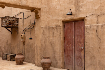 Old historic district Dubai. Ancient arabic wooden red front door with oriental pattern. Door surrounded by a clay wall. Entrance of the house.
