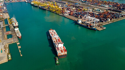 Fototapeta na wymiar container ship and shipping port loading and unloading cargo from container ship import and export by crane for distributing goods by trailers transported to customers and dealers, aerial view
