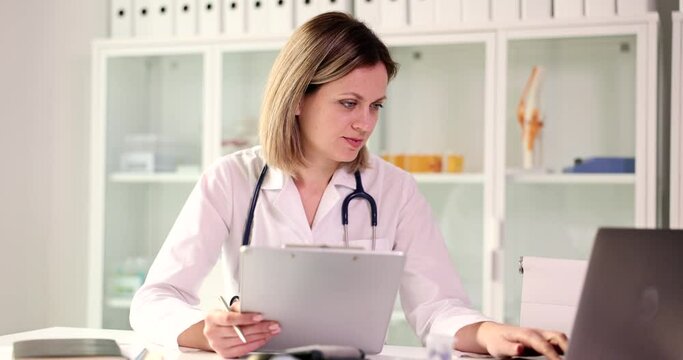 Female doctor with laptop reads documents in office. Health insurance and health examination