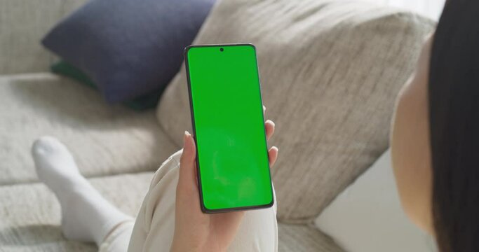 녹색 목업 화면이 떠 있는 스마트폰을 사용하는 여성을 어깨 너머로 본 영상