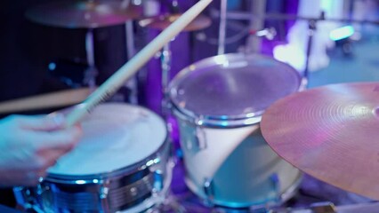A young man drummer plays a drum kit in a music studio. Creates music and art. Drum set, drum kit in dark, drummer plays. The musician is playing. Drummer plays a concert.