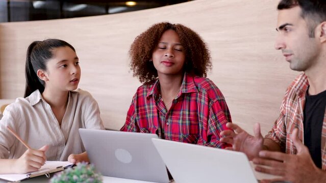 4K Multiethnic student girls writing lecture in class while Caucasian teacher man or tutor teaching in class, cheerful high school pupils studying in library with laptops, modern learning lifestyles