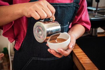 Barista pouring milk into coffee making a cappuccino. Barista making cappuccino,Professional bartender preparing coffee drink