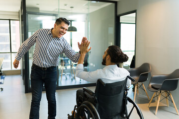 Happy businessman giving high five to disabled colleague in office