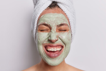 Close up shot of cheerful young woman gracefully applies beauty mask to her face immersing herself...