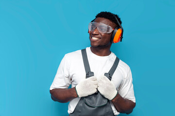 handyman in uniform and construction goggles looks away on blue isolated background
