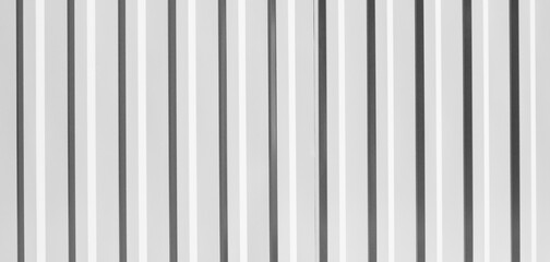 Corrugated metal fence. Metal profile fence in black and white. Texture of ribbed metal, sheets.