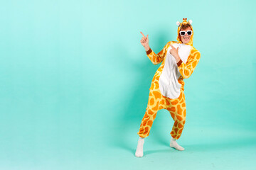 young funny guy in orange giraffe pajamas dances at party in sunglasses and points back