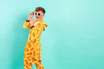 young funny guy in orange giraffe pajamas dances at party in sunglasses and points back