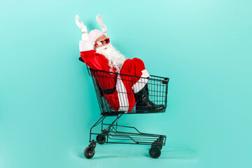 santa claus shopper in sunglasses and suit jumps and flies with empty shopping cart to the store