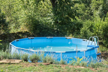 Round plastic swimming pool in countryside house backyard