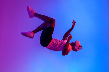 african american man in virtual reality glasses flies and falls in the air in neon lighting, the...