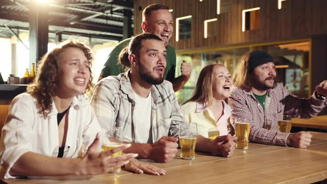 Cheerful people, friends sitting in bar, attentively watching football match translation, drinking beer, having fun. Concept of sport competition, hobby, lifestyle, human emotions, fun