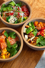 poke bowl composition: tuna, salmon, fried paneer cheese with avocado, mango, radish, rice and...