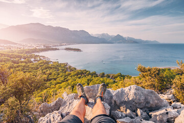 Hiker legs with trekking shoes on top of the canyon cliff with view of Kemer sea coast. Outdoors...