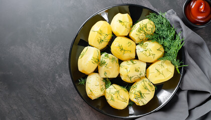 Delicious boiled potatoes with dill in a black plate on a dark background. Top view.