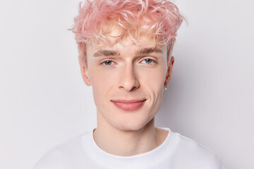 Portrait of handsome young pink haired man dressed in casual clothes smiles gladfully concentrated...