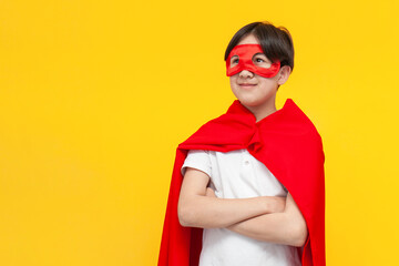 asian boy of twelve years old in superman costume on yellow isolated background, korean child in red mask