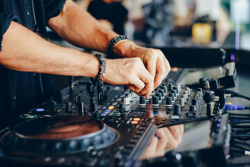 Hands of a DJ working with a mixing console close-up.