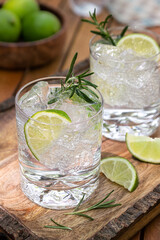 Gin and tonic cocktail garnished with lime and rosemary